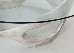 This is a detail of an organic, sculpted wood coffee table with a glass top