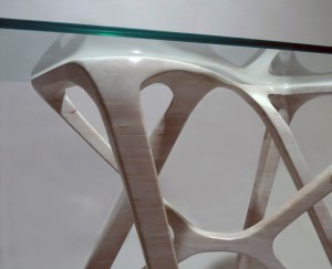 Photo of a detail from a sculpted wood desk base with a glass top