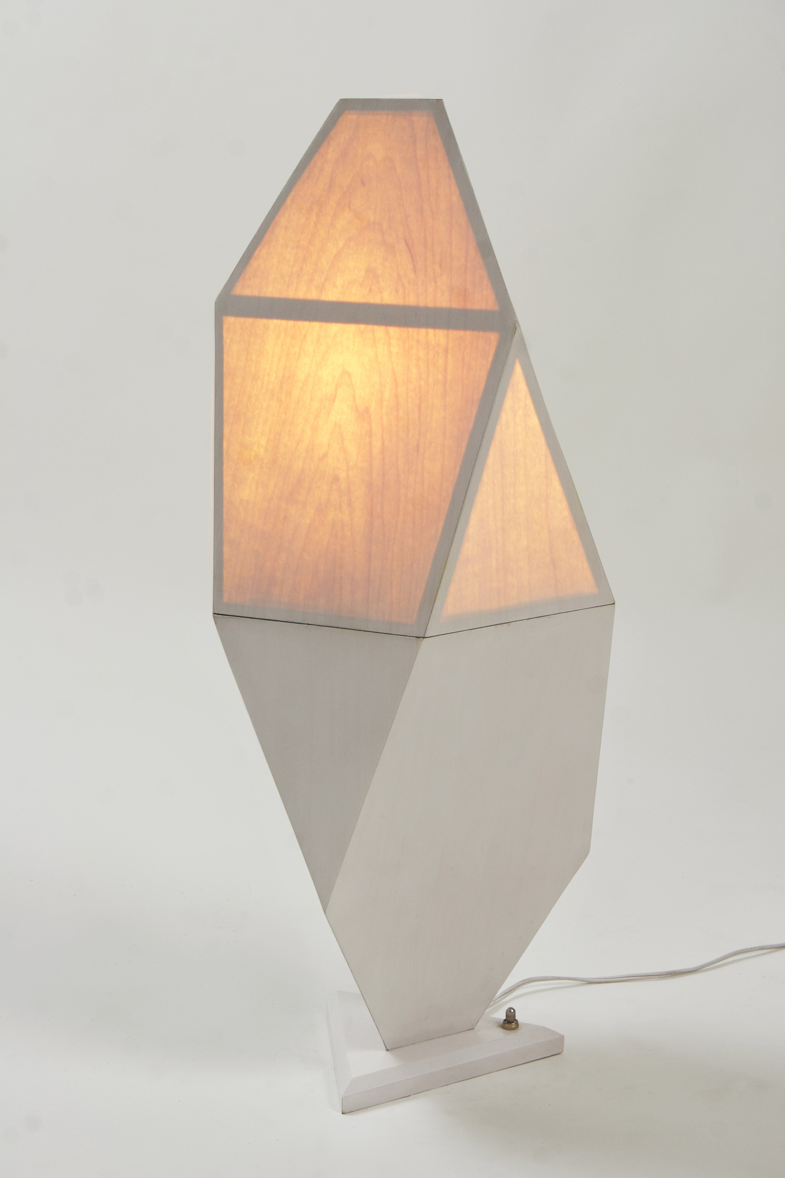 This photo shows a lamp made of geometric shapes covered with wood veneer, with the top half lit