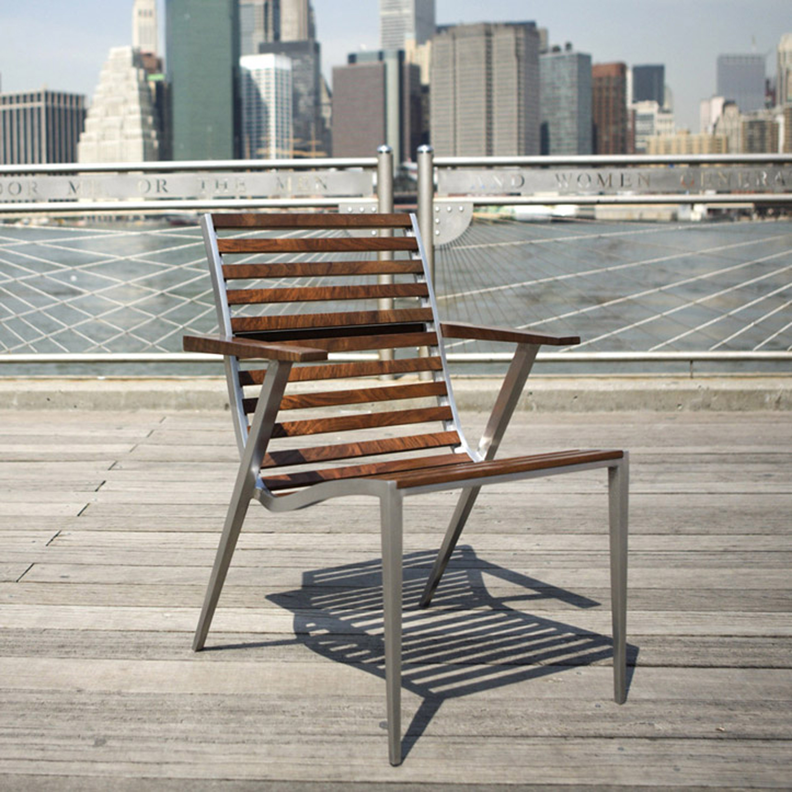 Dining chair made from cast aluminum and walnut shown on a promenade by the river