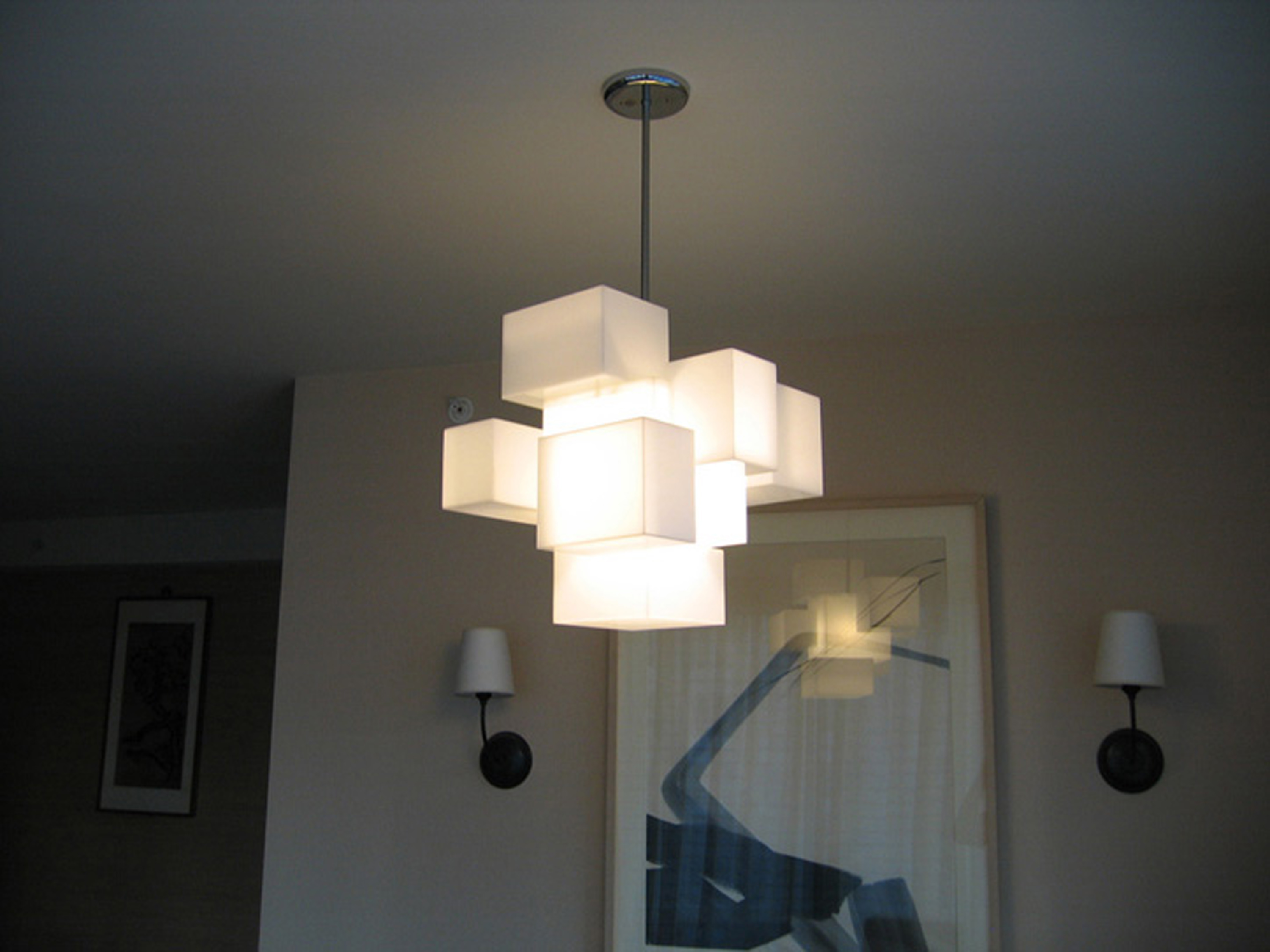 This is a photo of a cloud-like chandelier hanging in a living room, made from acrylic boxes, using an LED bulb